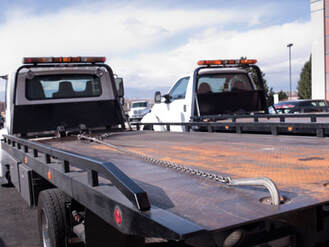 2 white flat bed tow trucks